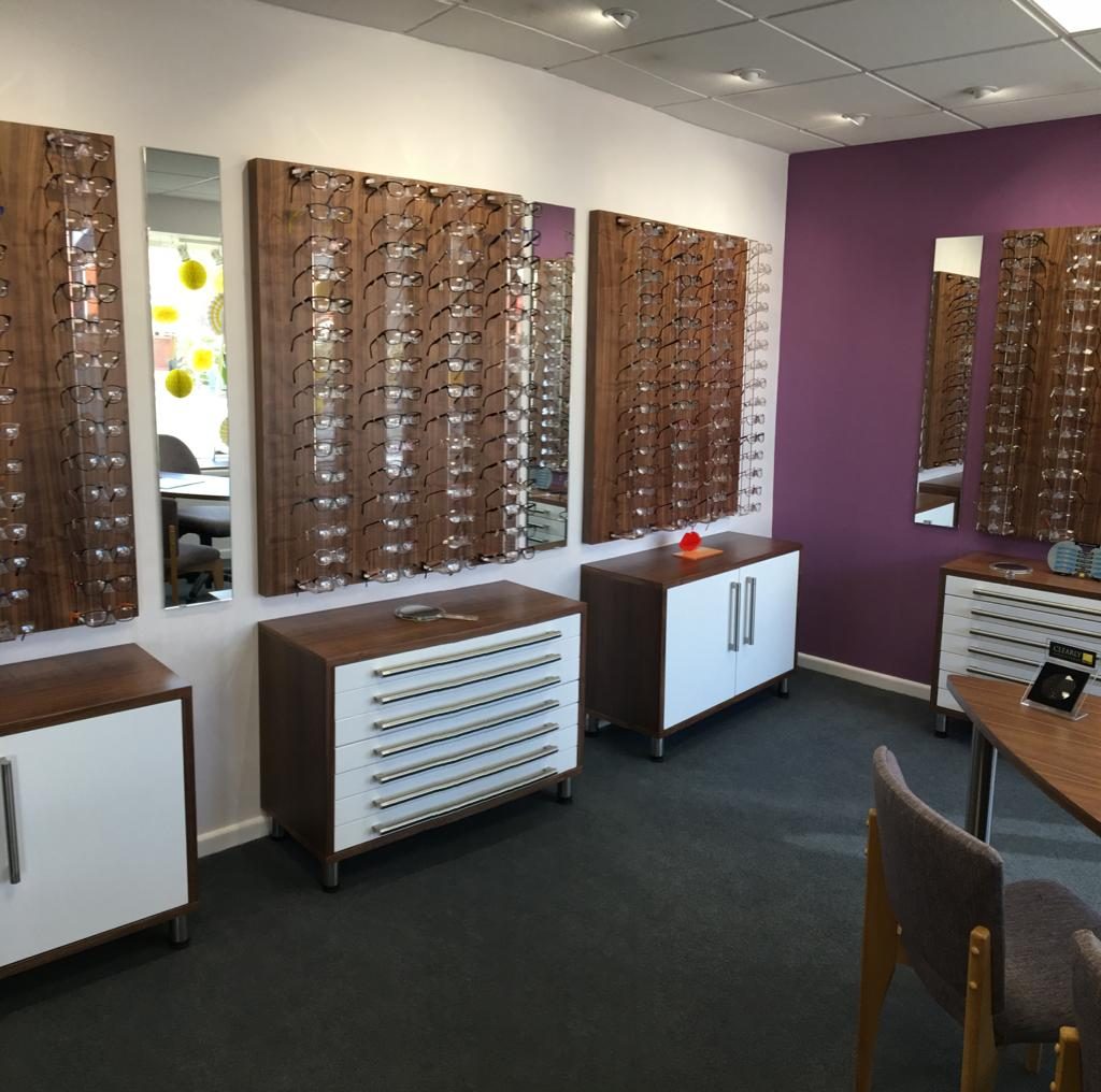 View inside an optician's showing display stands with multiple pairs of glasses.